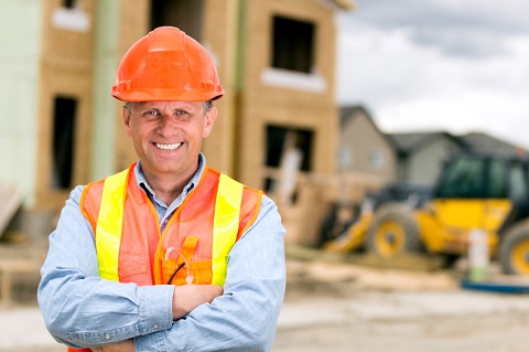 Builder with Hardhat in Front of Construction Site Builder with Hardhat in Front of Construction Site